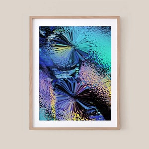 Op de afbeelding: Abstracte kunstprint met twee kleurrijke, gestileerde bloemen in een kleurenschema van blauw, groen, paars en geel.