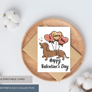 Puede incluir: Una tarjeta de San Valentín con un perro salchicha marrón sosteniendo globos en forma de corazón que dicen "I Love You". La tarjeta está sobre un plato de madera con un sobre marrón. El texto "Happy Valentine's Day" está debajo.
