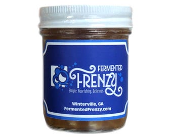 May include: A clear glass jar with a white screw-top lid containing a brown fermented food product. The blue label features the white text Fermented Frenzy, Simple. Nourishing. Delicious., Winterville, GA, and the website FermentedFrenzy.com.