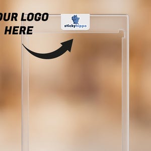 Peut inclure: Un étui en plastique transparent et rectangulaire avec une petite étiquette blanche portant le texte "stickyhippo" et une illustration d'hippopotame bleu. Le texte "YOUR LOGO HERE" est au-dessus d'une flèche noire incurvée.