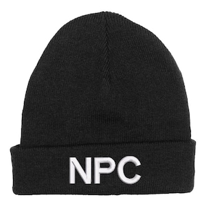 Puede incluir: Gorro de punto negro con las letras blancas bordadas "NPC" en la parte delantera. El gorro tiene un dobladillo doblado y una parte superior redondeada. El sombrero está hecho de un material de punto suave.