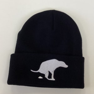 Gorro negro peculiar con bordado de silueta de caca de perro blanco.