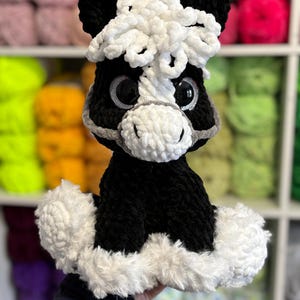 Another version of Hollie the Horse made with black and white yarn, featuring a curly mane and matching fluffy base. A creative variation showing how the digital crochet pattern can be customized.