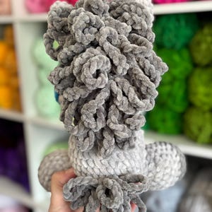 Rear view of the gray Hollie the Horse plushie, focusing on the curly yarn mane and tail. Demonstrates the plushie’s full 3D structure as created from the pattern.
