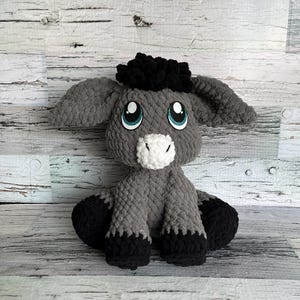 Dark gray version of Dylan the Donkey crochet plush made with soft yarn and teal eyes.