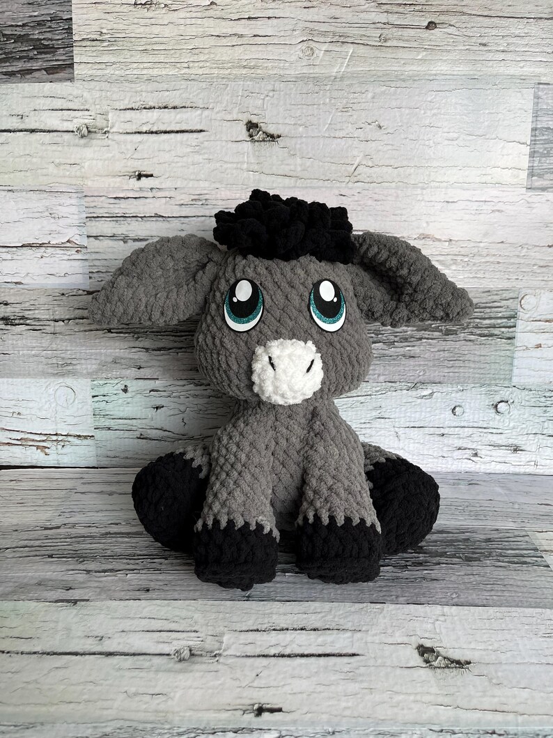 Dark gray version of Dylan the Donkey crochet plush made with soft yarn and teal eyes.