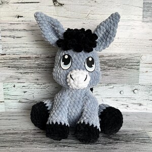 Gray Dylan the Donkey plush toy crocheted with black hooves and expressive eyes.