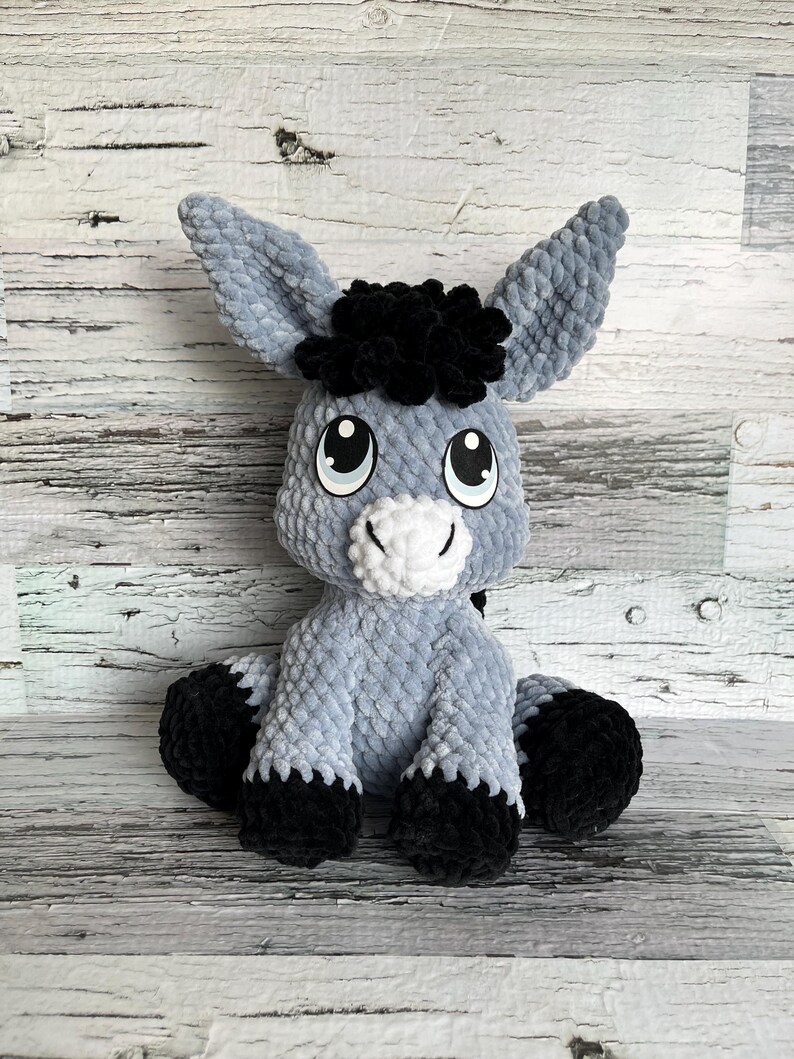 Gray Dylan the Donkey plush toy crocheted with black hooves and expressive eyes.