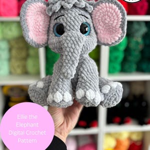 Puede incluir: Un elefante de ganchillo gris hecho a mano con orejas forradas de rosa y ojos azules. El elefante tiene detalles blancos en las patas y está etiquetado como "Ellie the Elephant Digital Crochet Pattern". La imagen también incluye el texto "Digital item not physical item".