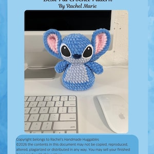 May include: A blue crochet alien desk pal with pink inner ears, sitting on a desk next to a keyboard and mouse. The text "Blue Alien Desk Pal Crochet Pattern By Rachel Marie" is at the top.