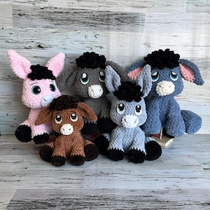 Group of plush donkeys made from Dylan the Donkey crochet pattern in multiple colors and sizes.