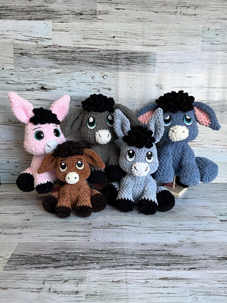 Group of plush donkeys made from Dylan the Donkey crochet pattern in multiple colors and sizes.