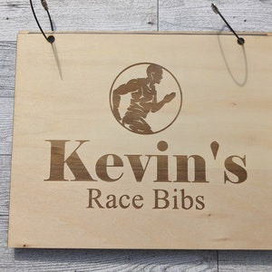 May include: Wooden sign with the text "Kevin's Race Bibs" and a silhouette of a runner in a circle.