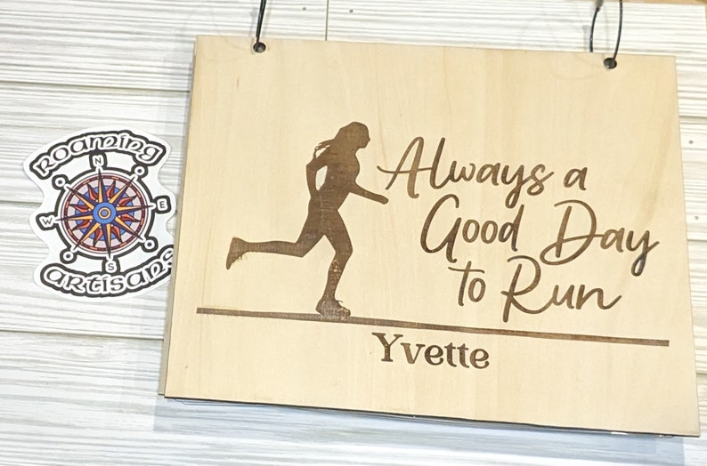 Pu&ograve; includere: Un cartello di legno con la silhouette di un corridore e il testo "Always a Good Day to Run" con il nome "Yvette" in basso.
