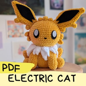 Könnte beinhalten: Ein gehäkeltes gelbes und weißes elektrisches Katzen-Plüschtier. Das Spielzeug hat schwarze Ohren und große, runde Augen. Das Spielzeug sitzt auf einer Holzoberfläche. Der Text "PDF ELECTRIC CAT" ist im Bild sichtbar.