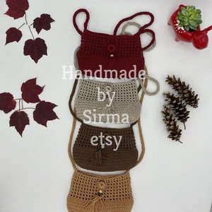 May include: Three crocheted bags with tassels and wooden beads. The bags are stacked on top of each other. The top bag is red, the middle bag is beige, and the bottom bag is brown. The text "Handmade by Sirma etsy" is visible on the image.