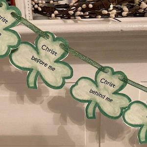 May include: A green shamrock garland with the words "Christ with me", "Christ before me", "Christ behind me", and "Christ in me" written on each shamrock.