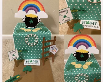 Op de afbeelding: Een groene en witte stippen doos met een regenboog, pot met goud en een ladder. De doos heeft een bord met de tekst "Volg de regenboog" en een ander bord met de tekst "Leprechaun Crossing". De doos heeft ook een bord met de tekst "Thuis Geen Ongehoord Zone".
