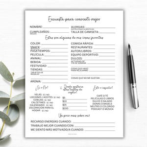May include: A white questionnaire with black text and a black pen. The questionnaire includes sections for personal details, favourite things, and preferences. The text is in Spanish. A sprig of eucalyptus is in the background.