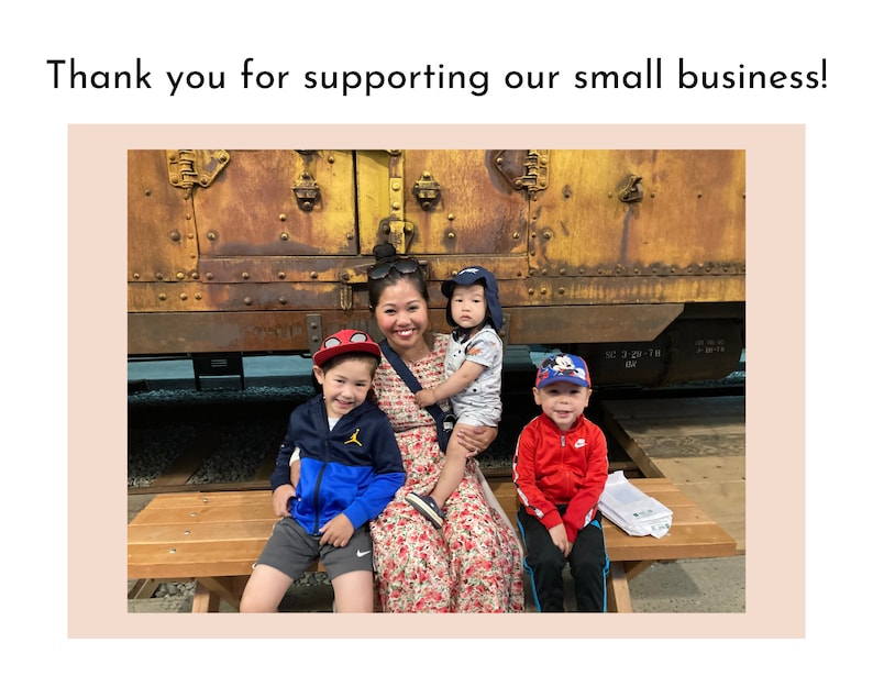 May include: A woman and three children stand in front of a rusty train car. The woman is wearing a floral dress and the children are wearing casual clothing. The children are smiling and the woman is looking at the camera.