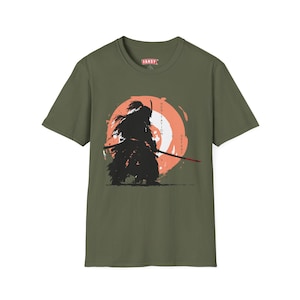 Puede incluir: Camiseta verde oliva con un diseño de guerrero samurái negro, sobre un fondo circular naranja. El diseño incluye las palabras "Hesitation" y "Defeat". La camiseta tiene la palabra "FANSY" en el pecho.
