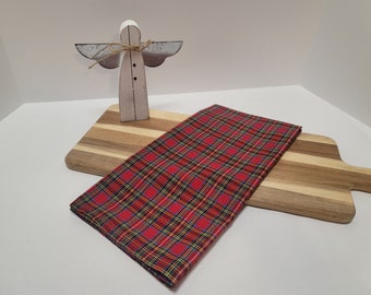 Puede incluir: Servilleta de tela a cuadros rojos y negros sobre una tabla de cortar de madera con una figurita de ángel de madera blanca.