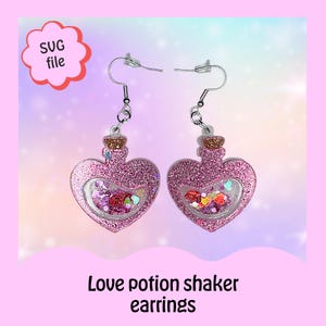 May include: A pair of pink heart-shaped earrings with a glitter finish. Each earring features a clear bottle filled with colorful glitter and hearts. The earrings are attached to silver hooks.
