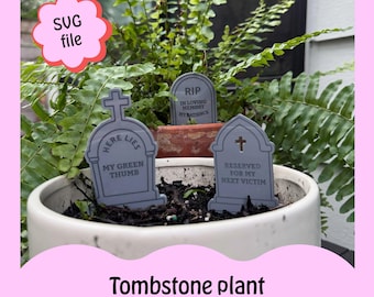 May include: Four gray tombstone-shaped plant stakes with humorous sayings. The stakes are in a pot with green plants. The stakes read "Here Lies My Green Thumb", "RIP In Loving Memory My Patience", "Reserved For My Next Victim", and "SVG File".