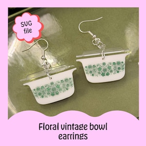 May include: Floral vintage bowl earrings. These earrings feature a miniature white bowl design with a clear lid and green floral pattern. The earrings are suspended from silver-colored fish hook ear wires. The text "SVG file" is in a pink bubble. The text "Floral vintage bowl earrings" is at the bottom.
