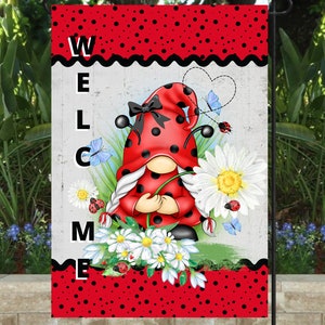 May include: A red and black ladybug gnome holding a white daisy with a welcome sign in the background. The sign has a black and white wavy border and the letters are black.