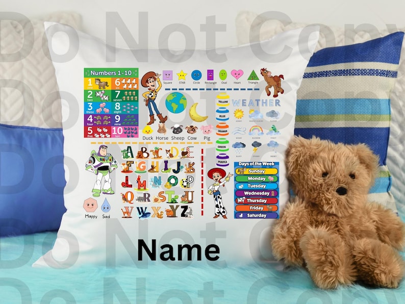 Op de afbeelding: Witte kussensloop met educatieve afbeeldingen, waaronder cijfers, letters en weersymbolen. Bevat stripfiguren en de tekst "Name". Een teddybeer en kussens zijn op de achtergrond.