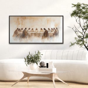 The Last Supper wall art is a large Christian canvas print hanging in a minimalist living room above the couch in neutral tones. This modern Christian art shows Jesus having His Last Supper with His twelve disciples. This Framed Last Supper Painting is a Christian print or Catholic art and is a long horizontal wall art with a black frame. Religious artwork, Last Supper print, Christian wall art, Jesus Wall Art, Above Bed Art, Last Supper Art, Last Supper Art Print, Jesus Painting, Jesus Art