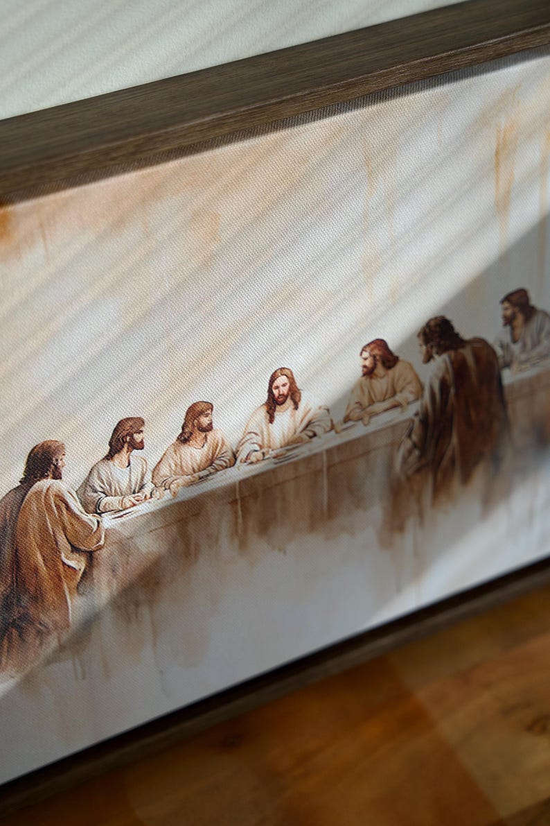 May include: A framed canvas print of the Last Supper. The image shows figures in robes seated at a long table. The colour palette includes warm tones of brown, beige, and white, with a wooden frame.