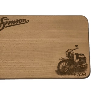 Könnte beinhalten: Ein Holzbrett zum Schneiden mit einem Laser-gravierten Design eines Simson KR51 Mopeds. Das Brett hat das Wort "Simson" in einer kursiv geschriebenen Schrift oben eingraviert.