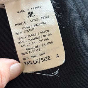 May include: White tag with black text detailing the fabric composition and size of a garment. The tag reads "Made in France", "Modele / Style 28209", "Tissu / Material", "100% Acetate", "76% Viscose / Rayon", "20% Polyamide / Nylon", "4% Coton / Cotton", "Doublure / Lining", "100% Acetate", "100% Soie / Silk", "Taille / Size A".