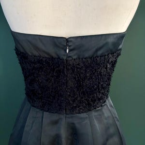 May include: A black strapless dress with a fluffy, textured bodice and a smooth, flowing skirt.