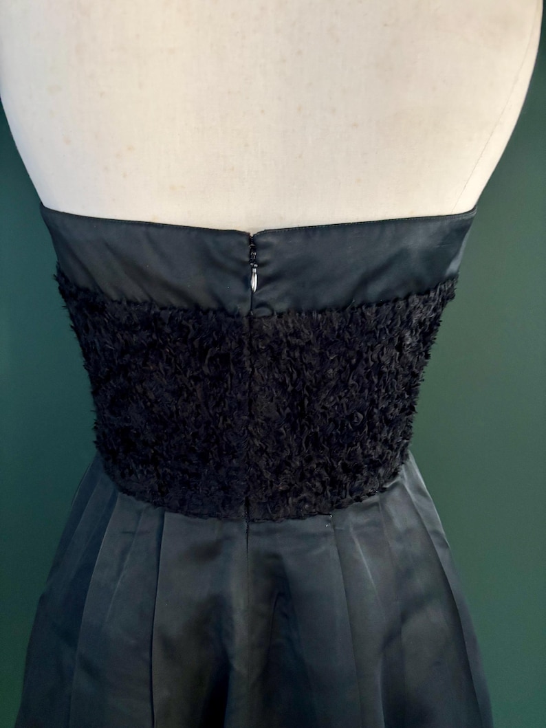 May include: A black strapless dress with a fluffy, textured bodice and a smooth, flowing skirt.