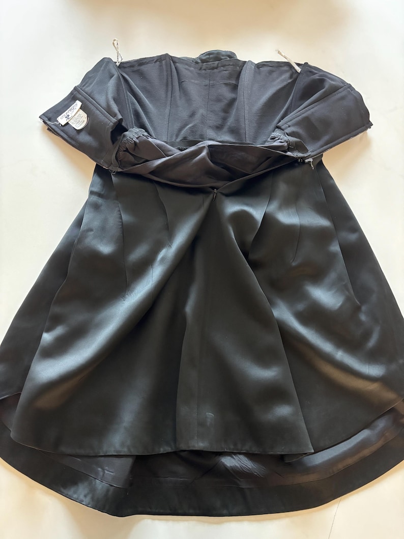 May include: A black strapless satin dress with a zipper in the back. The dress is fully lined and has a fitted bodice and a full skirt.