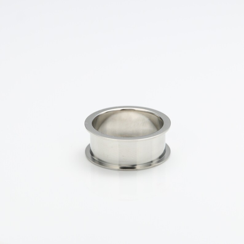 May include: A silver metal ring with a smooth, rounded surface. The ring is designed to be used as a spacer or connector for plumbing or other industrial applications.