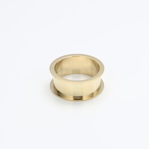 May include: A gold-colored metal ring with a wide band and a smooth, polished finish.