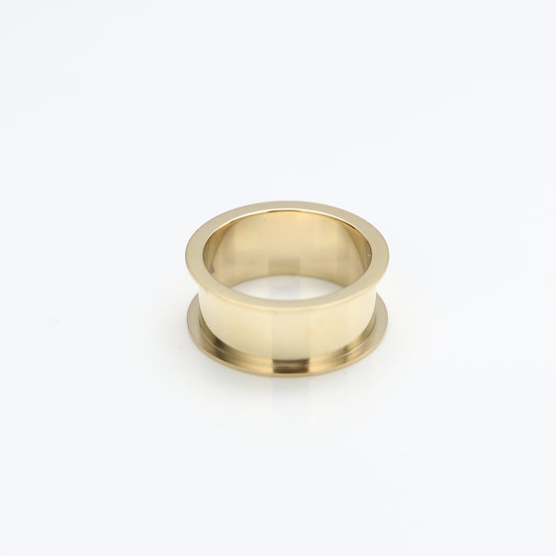 May include: A gold-colored metal ring with a wide band and a smooth, polished finish.