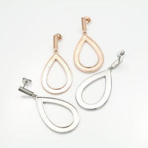 May include: A pair of teardrop-shaped earrings with a double-ring design. One earring is silver and the other is rose gold.