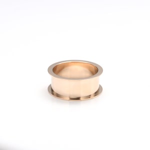 May include: A gold-colored metal ring with a wide band and a slightly rounded top.