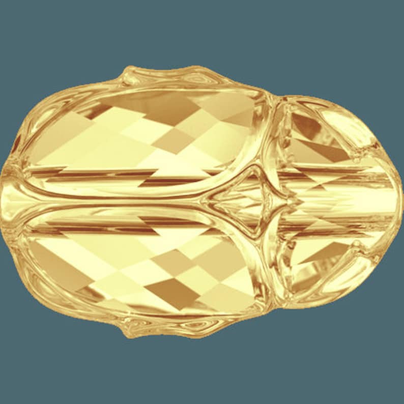 May include: A gold-colored, faceted, glass ornament with a smooth, rounded surface. The ornament has a unique, abstract design.
