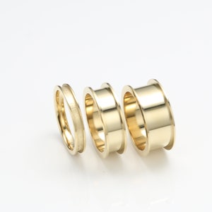 May include: Three gold rings of different sizes, stacked together. The rings are smooth and shiny.