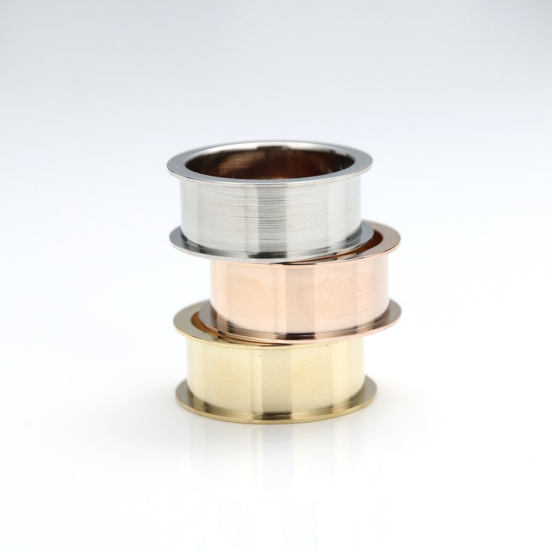 May include: Three stacked rings, one silver, one rose gold, and one gold. The rings are all smooth and have a polished finish.