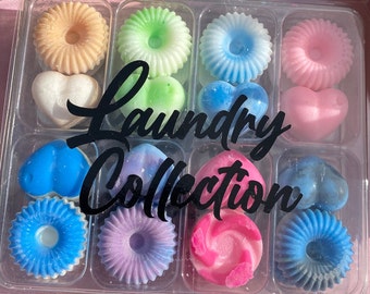 Könnte beinhalten: Ein transparenter Plastikbehälter gefüllt mit 12 bunten Wachsschmelzen in verschiedenen Formen, darunter Herzen und Kreise. Die Wachsschmelzen sind in einem Raster angeordnet und mit "Laundry Collection" beschriftet.