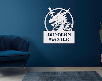 May include: White metal wall art featuring a dragon, sword, and a D20 die, with the text "DUNGEON MASTER". The artwork is mounted on a dark blue wall. A blue armchair and a potted plant are in the background.