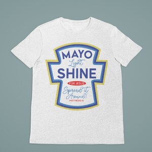 Puede incluir: Camiseta blanca con un gr&aacute;fico azul y amarillo de un tarro de mayonesa con el texto "Mayo Light Shine" y "For Jesus Spread it Around! Matthew 5:16"