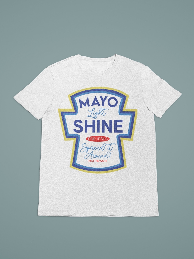 Puede incluir: Camiseta blanca con un gr&aacute;fico azul y amarillo de un tarro de mayonesa con el texto "Mayo Light Shine" y "For Jesus Spread it Around! Matthew 5:16"
